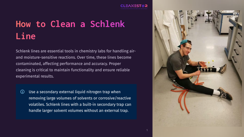 A Man In A Chemistry Lab Wearing A Gray T-Shirt And Jeans Is Seated On The Floor, Working On A Schlenk Line, With A Large Orange Tube Lying In Front Of Him. The Lab Is Well-Lit With White Walls And A Tiled Floor.