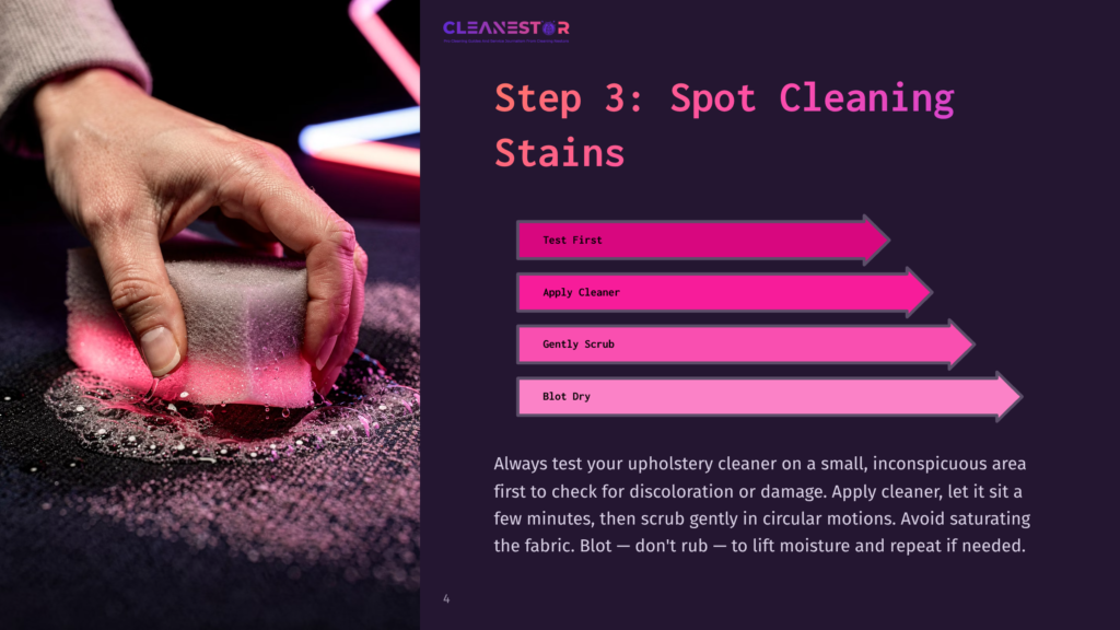 Close-Up Of A Hand Gently Scrubbing A Dark Fabric With A Pink Sponge And Cleaning Solution, Demonstrating Spot Cleaning Techniques For Upholstery.