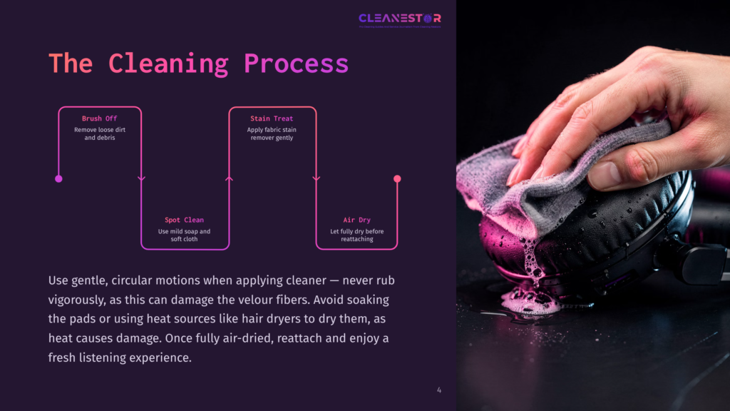 A Hand Gently Wipes Pink Cleaning Solution From Black Headphones With A Grey Cloth, Showing The Cleaning Process For Removing Dust And Stains.