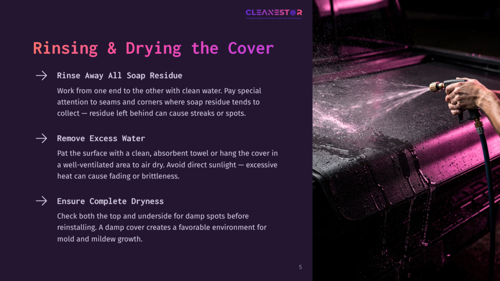A Person'S Hand Sprays Water Onto A Dark, Textured Surface, Rinsing Away Soap Residue. The Image Focuses On The Water Droplets And The Cleaning Process.