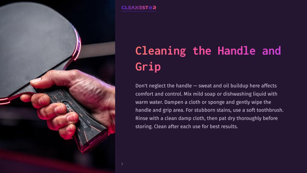 Close-Up Of A Hand Holding A Ping Pong Paddle, With Focus On Cleaning The Textured Handle And Grip With A Toothbrush And Damp Cloth.