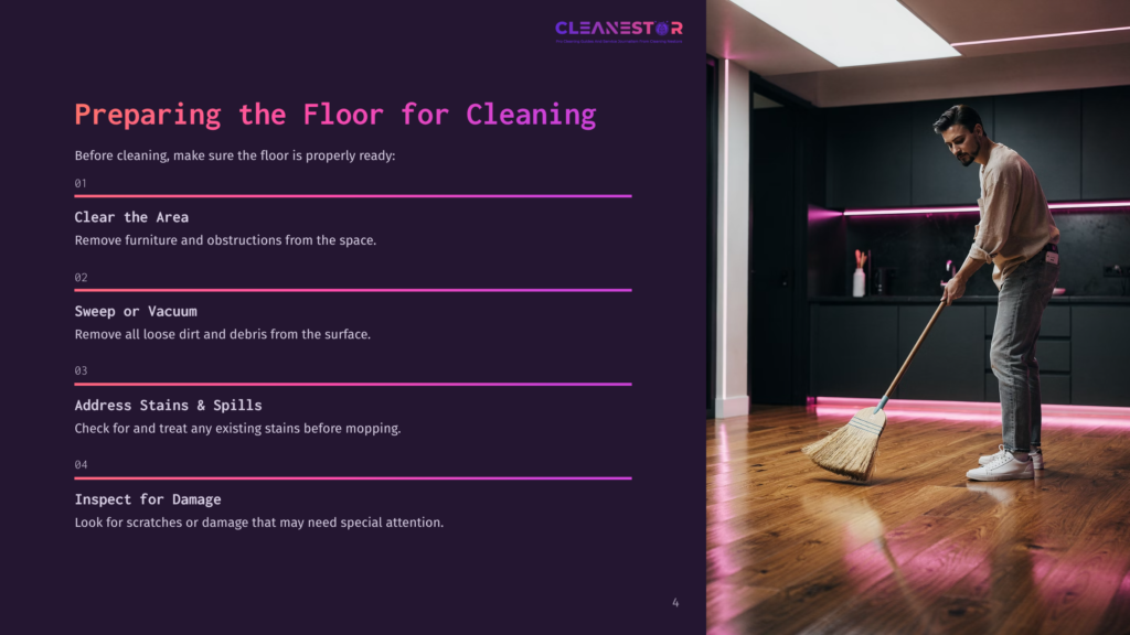 A Person Sweeping Cherry Hardwood Floors In A Modern Kitchen With Soft Lighting, Featuring A Dark Cabinet And Pink Accents.