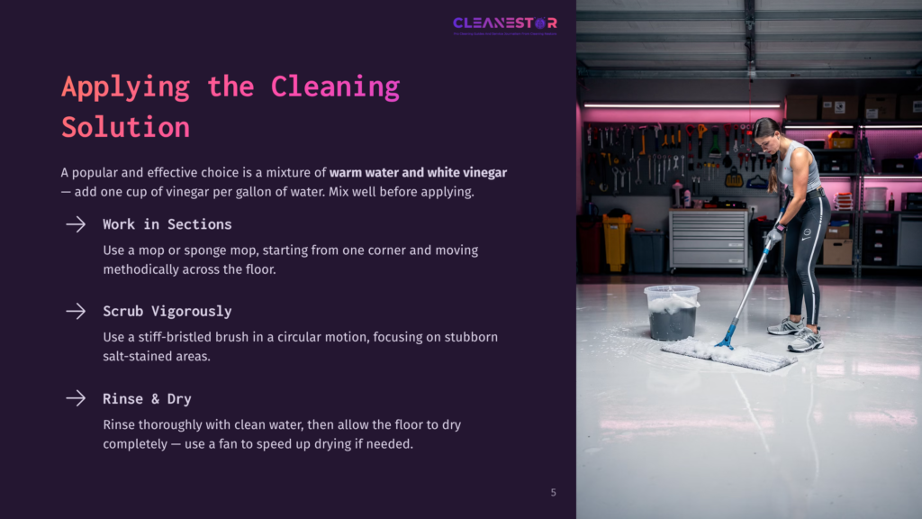 5 Applying The Cleaning Solution A Person Scrubbing A Shiny Garage Floor With A Bucket Of Cleaning Solution; Tools Hang On The Wall, With A Pink Accent Light In The Background.