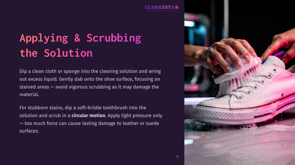 Close-Up Of Hands Cleaning White Canvas Sneakers With A Brush And Foamy Cleaning Solution, Showing The Process Of Applying And Scrubbing The Cleaning Solution To Remove Stains.